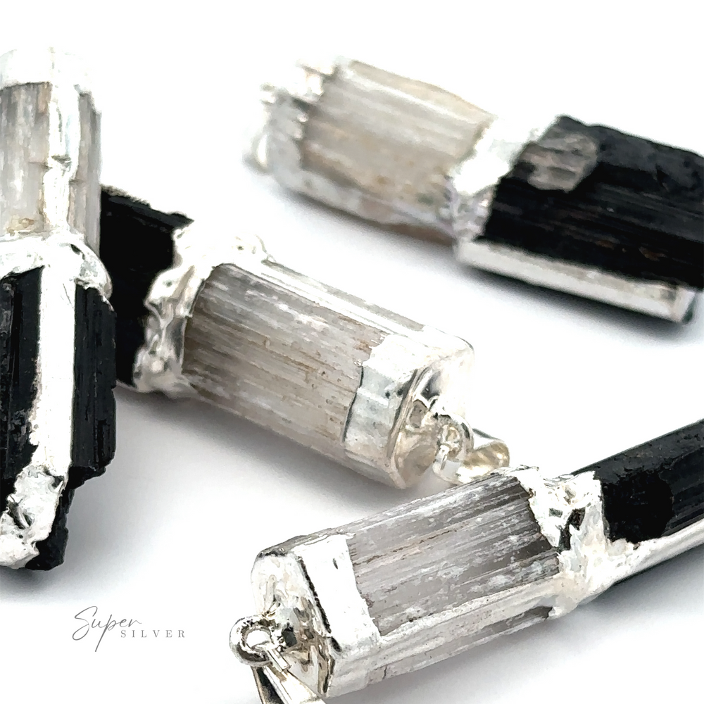 Close-up of black and white crystal pendant necklaces with silver caps on a white background, featuring a Tourmaline and Selenite Pendant known for its cleansing properties.