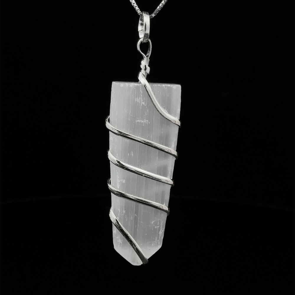 
                  
                    A Wire Wrapped Slab Pendant, hanging from a silver chain against a black background, exemplifies the allure of gemstone jewelry.
                  
                