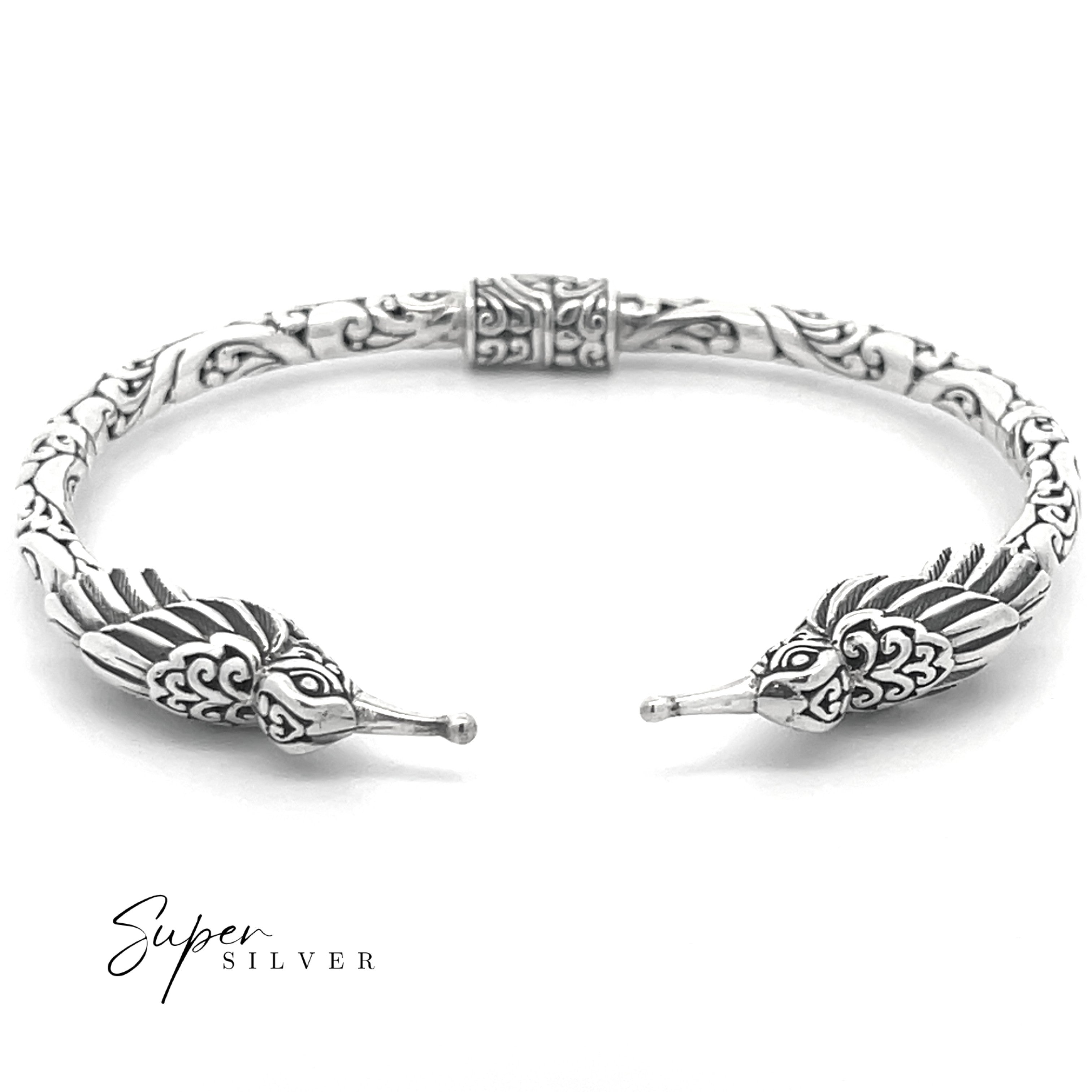 The Enchanting Hummingbird Hinge Bracelet is a sterling silver cuff with intricate patterns and two hummingbird heads facing each other, handcrafted by artisans. The "Super Silver" logo is displayed in the bottom left corner.