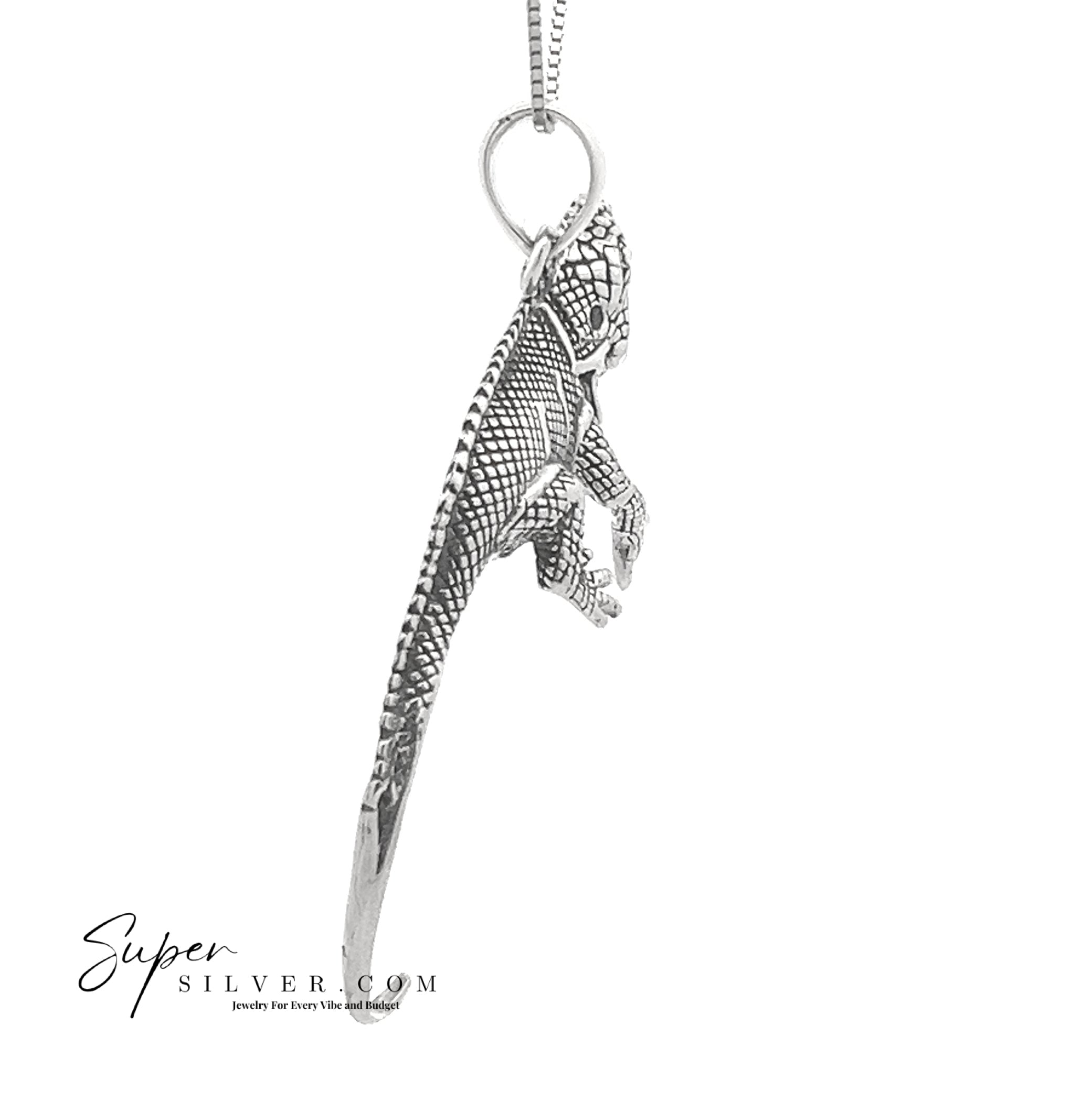 The Spirit of the Sun Iguana Pendant is a detailed, textured sterling silver dinosaur from the Artssina Collection. "Super Silver.com" appears in the bottom left, highlighting this unique pendant.