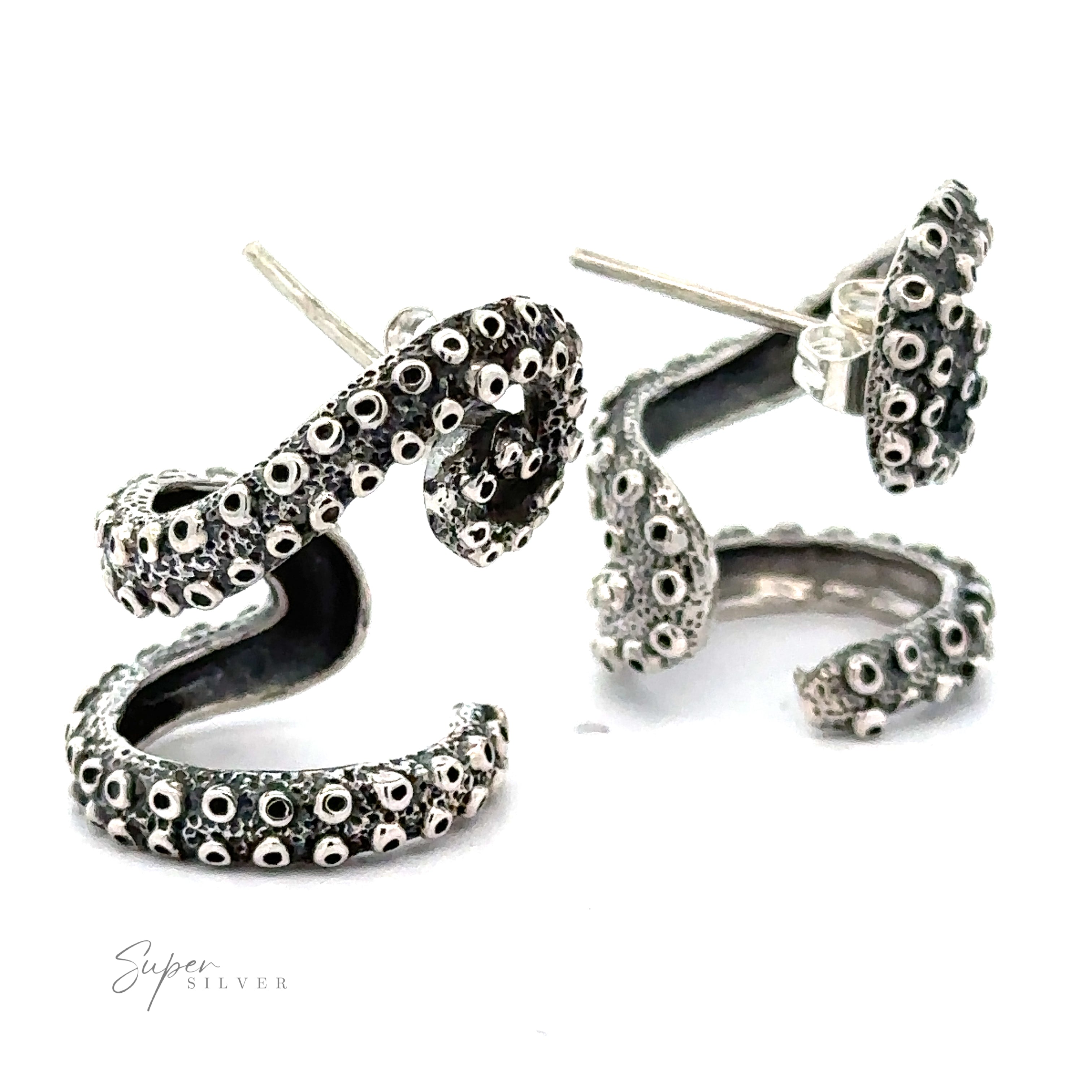 A pair of Curled Tentacle Earrings designed in the shape of octopus tentacles with detailed suction cups, presented on a white background. The handcrafted sterling silver adds a touch of elegance, and the logo "Super Silver" is visible in the bottom left corner.