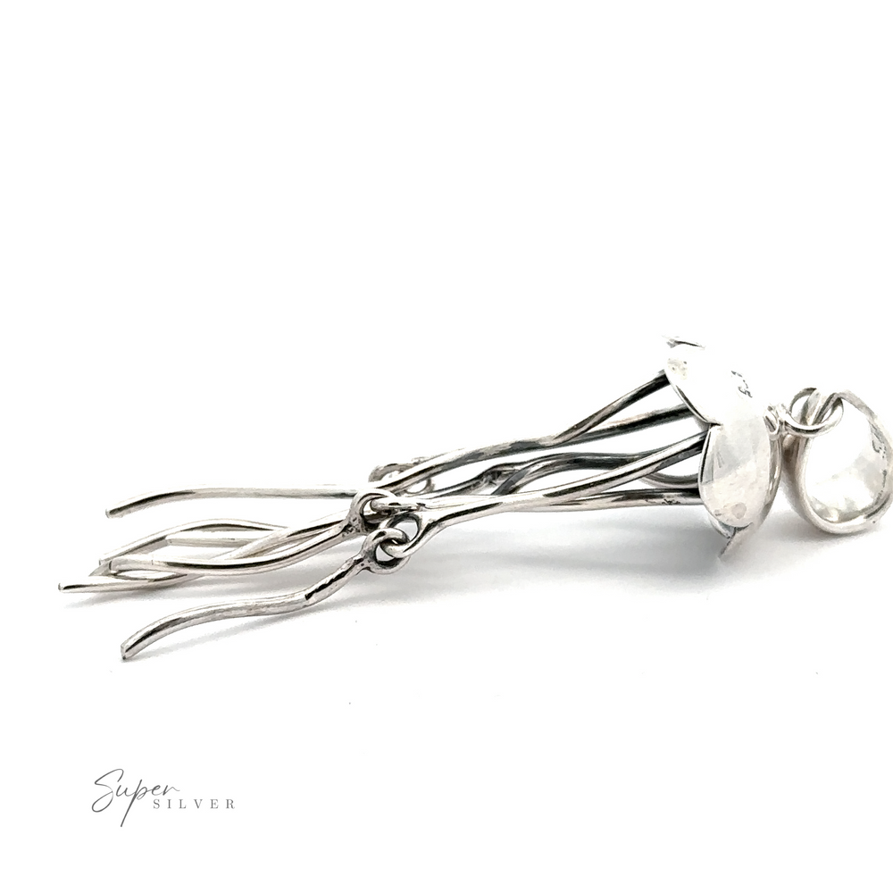 
                  
                    Pair of silver dangle earrings with elongated, wire-like elements and shell-shaped accents, resembling Moving Tentacle Jellyfish Pendants. Crafted from .925 Sterling Silver and part of the Artisan Collections. The brand's name, "Super Silver," appears in the bottom left corner. White background.
                  
                