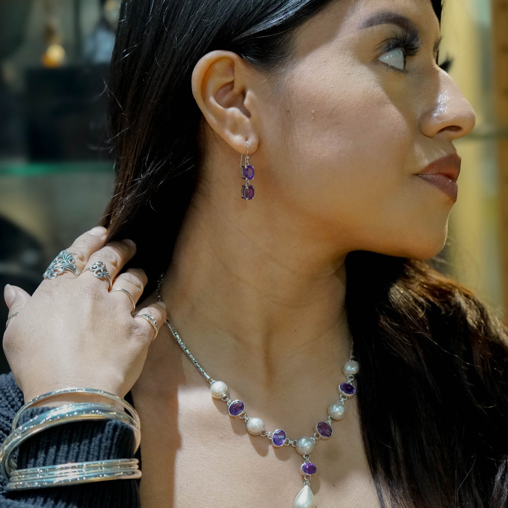 
                  
                    A woman with long dark hair is wearing a Stunning Pearl and Gemstone Statement Necklace, matching earrings, and multiple bracelets and rings. She is looking to the right and touching her hair with her left hand.
                  
                
