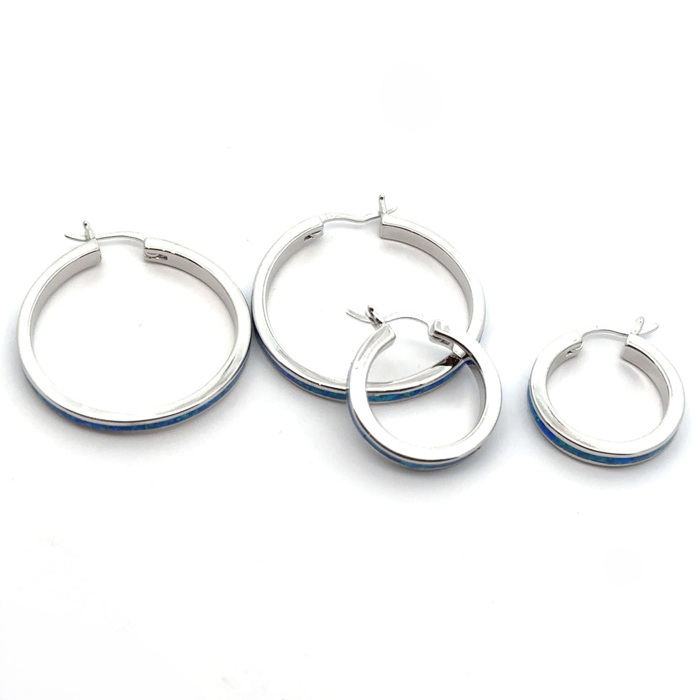 Blue Lab-Created Opal hoop earrings, available in two distinct sizes, stylishly displayed on a white background. The sparkling rhodium finish adds to their allure and sophistication.