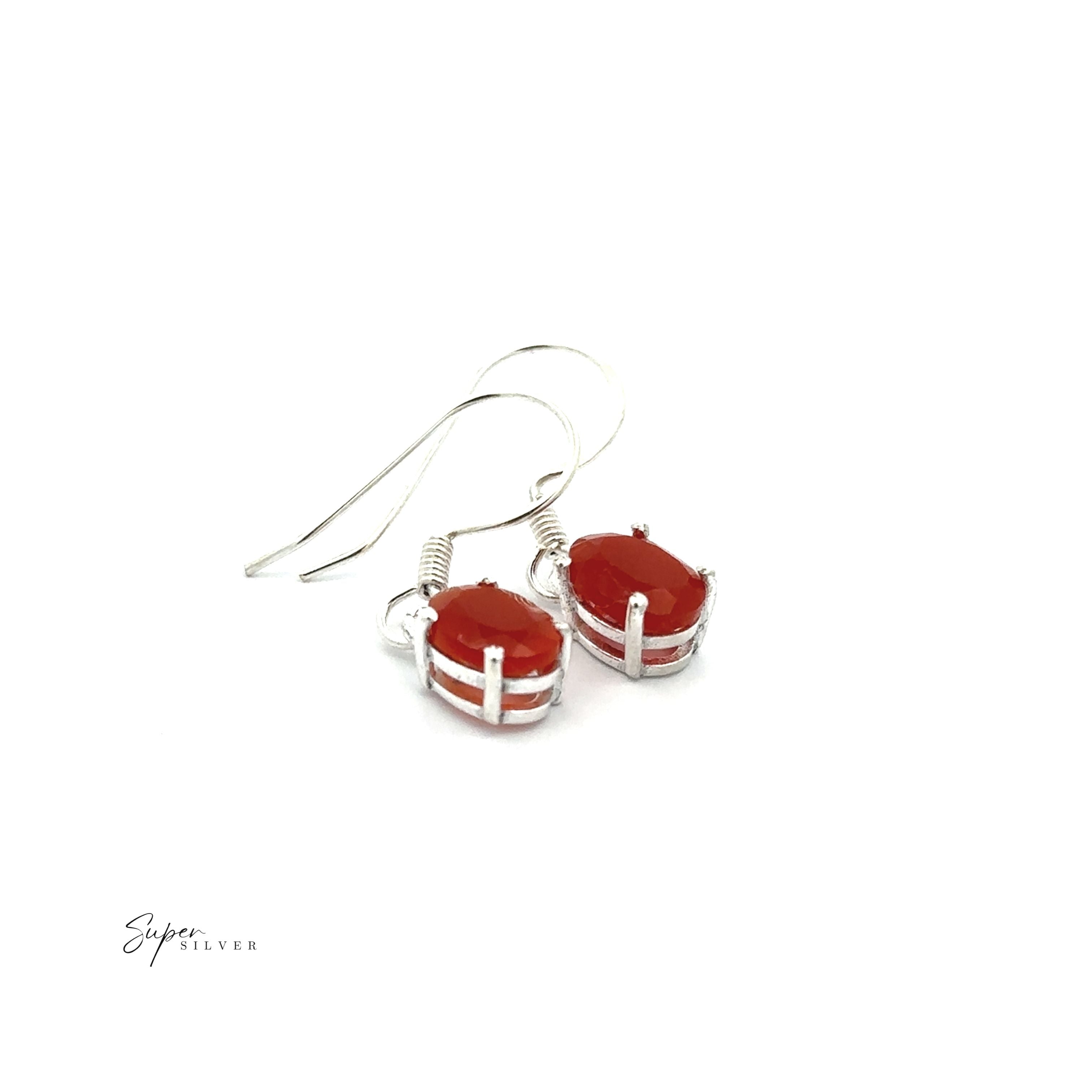 Brilliant Oval Gemstone Earrings: A pair of sterling silver earrings with oval red gemstones in prong settings, shown on a white background.