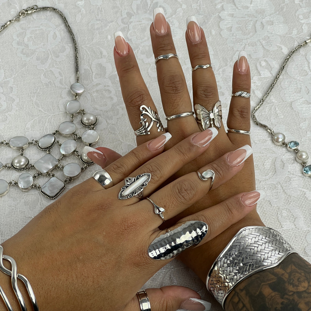
                  
                    A woman's hands adorned with a wide diamond shaped basket weave cuff bracelet, showcasing .925 Sterling Silver jewelry.
                  
                