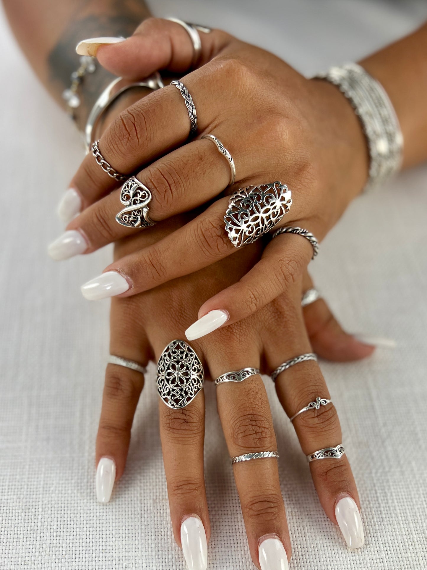 A woman's hands with intricate rings, showcasing a Floral Filigree Shield Ring.