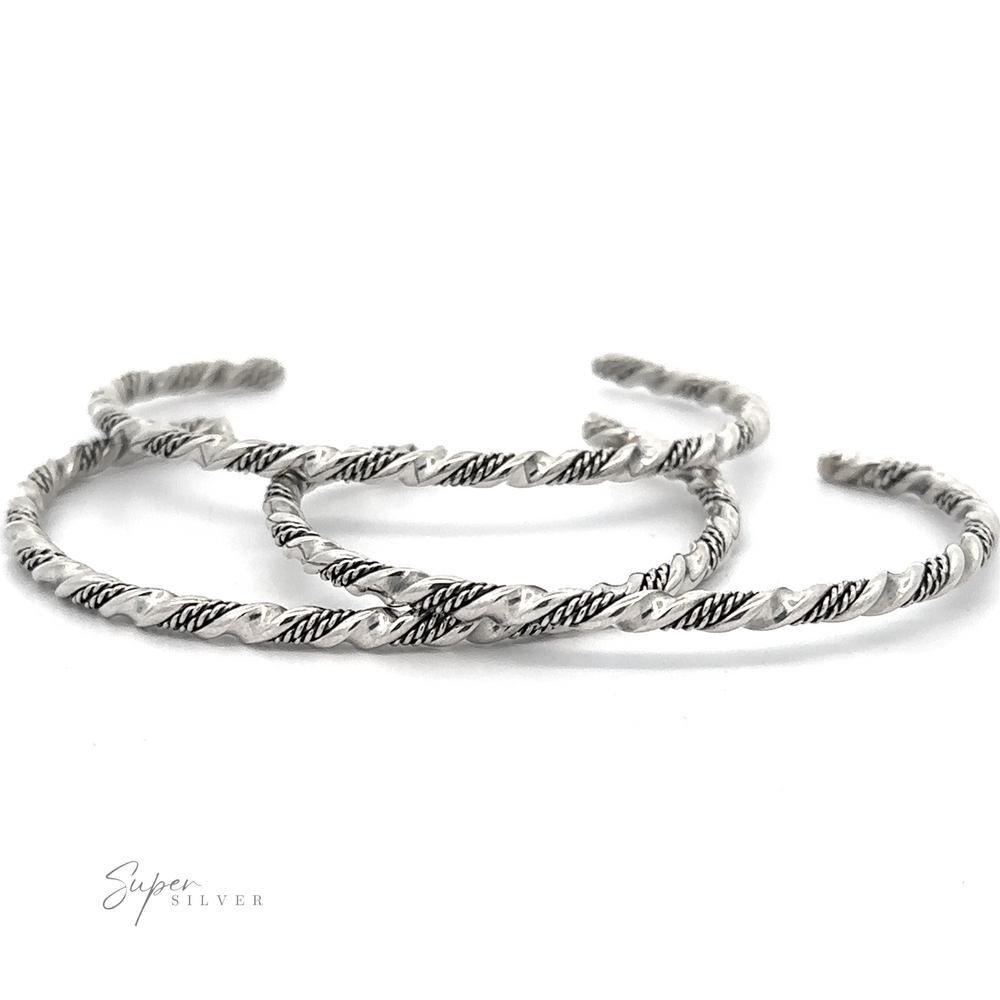 Three twisted, handmade Native American Handmade Silver Rope Twist Cuff bangles with intricate patterns are arranged on a white background. The brand 