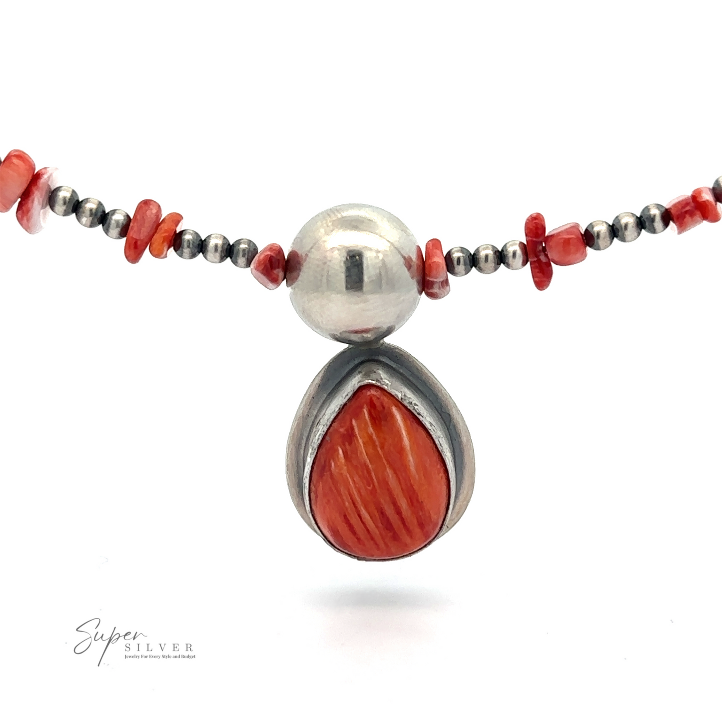 
                  
                    A close-up image of a necklace featuring a silver pendant with a teardrop-shaped red stone, surrounded by small red and silver beads. Created by Native American artisans, the brand name "Wrap Around Spiny Oyster Shell Choker Necklace" is visible at the bottom left.
                  
                