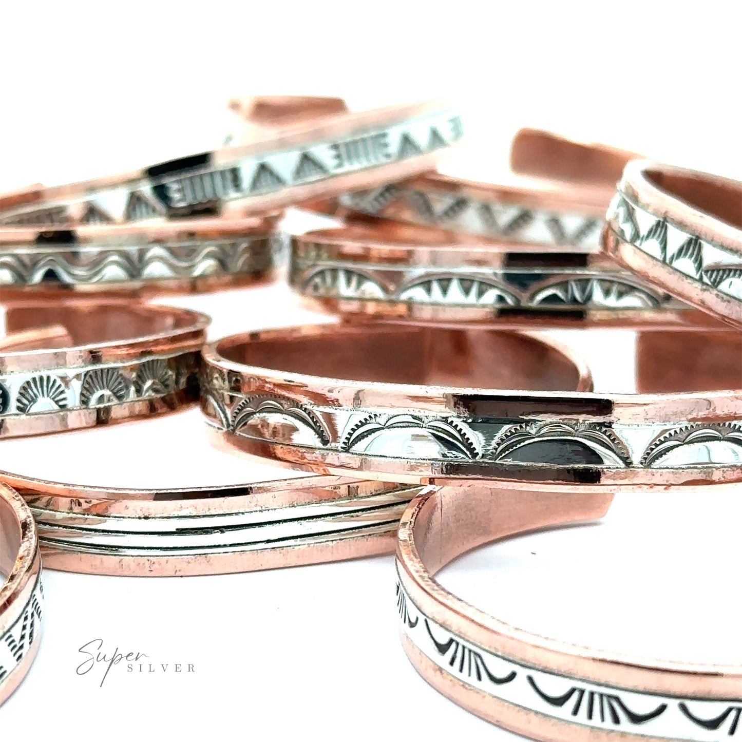 
                  
                    A collection of Native American Handmade Copper And Silver Bracelets with intricate geometric designs arranged on a white surface.
                  
                
