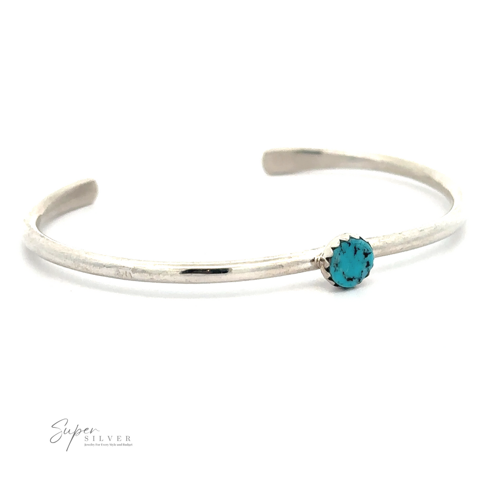 A thin .925 Sterling Silver bracelet featuring a small round Kingman Turquoise stone set in the center. The bracelet has an open cuff design. Logo "Stackable Native American Turquoise Cuff" in bottom left.