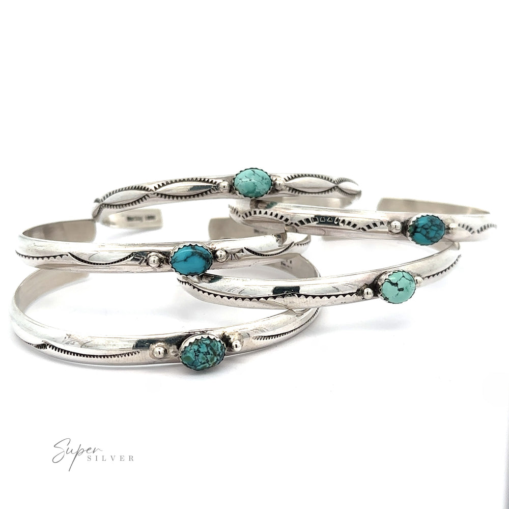 
                  
                    Four Striking Native American Turquoise Cuffs with Diamond Etching, each featuring Kingman Turquoise stones, are stacked together on a white surface. The cuffs have intricate detailing along the edges, reminiscent of a handcrafted Navajo cuff. The words "Super Silver" are in the bottom-left corner.
                  
                