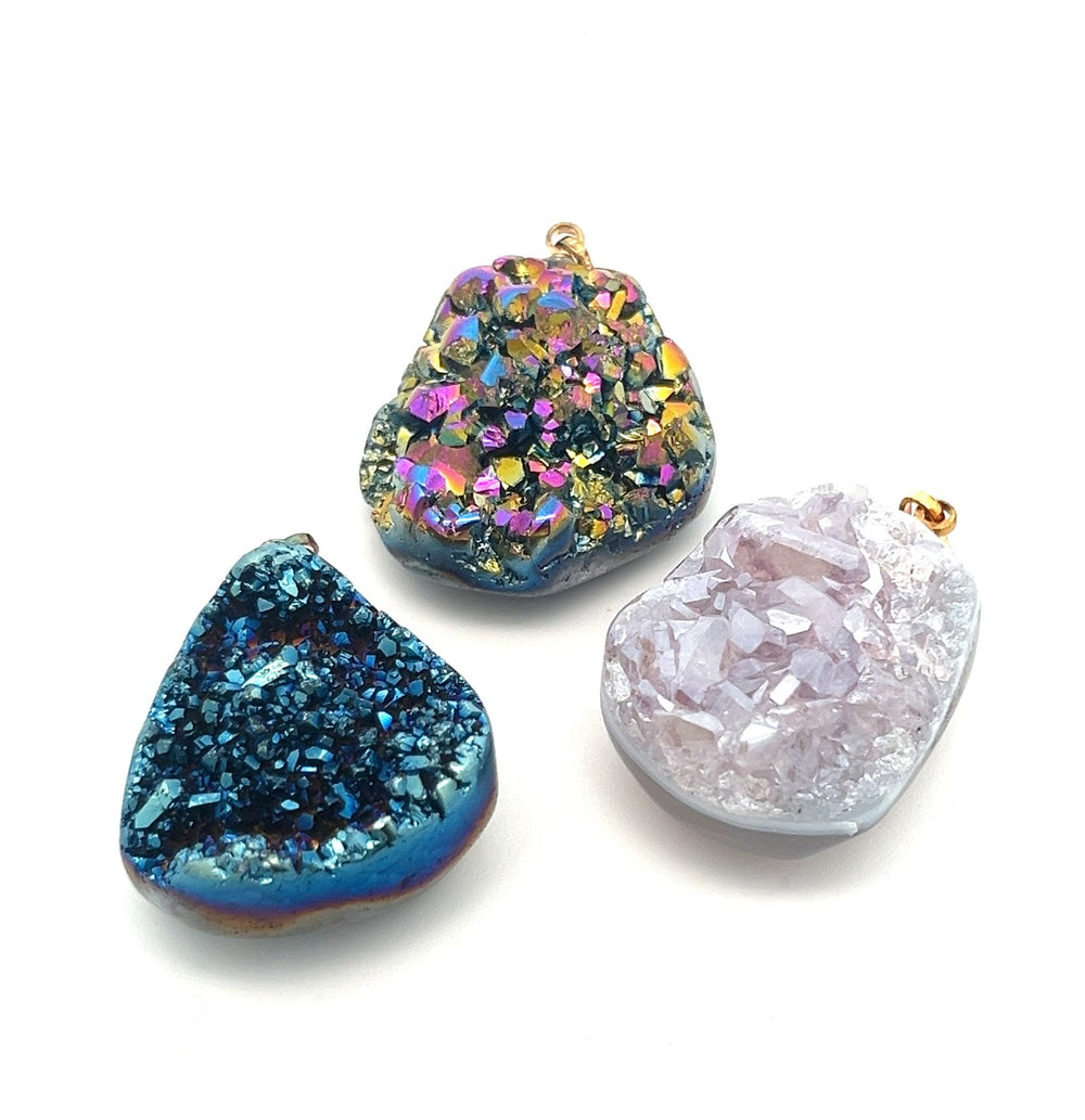 Three exquisite Dazzling Druzy Pendants in blue, multicolored, and pale pink hues, each attached to small gold-plated bails, displayed against a white background.