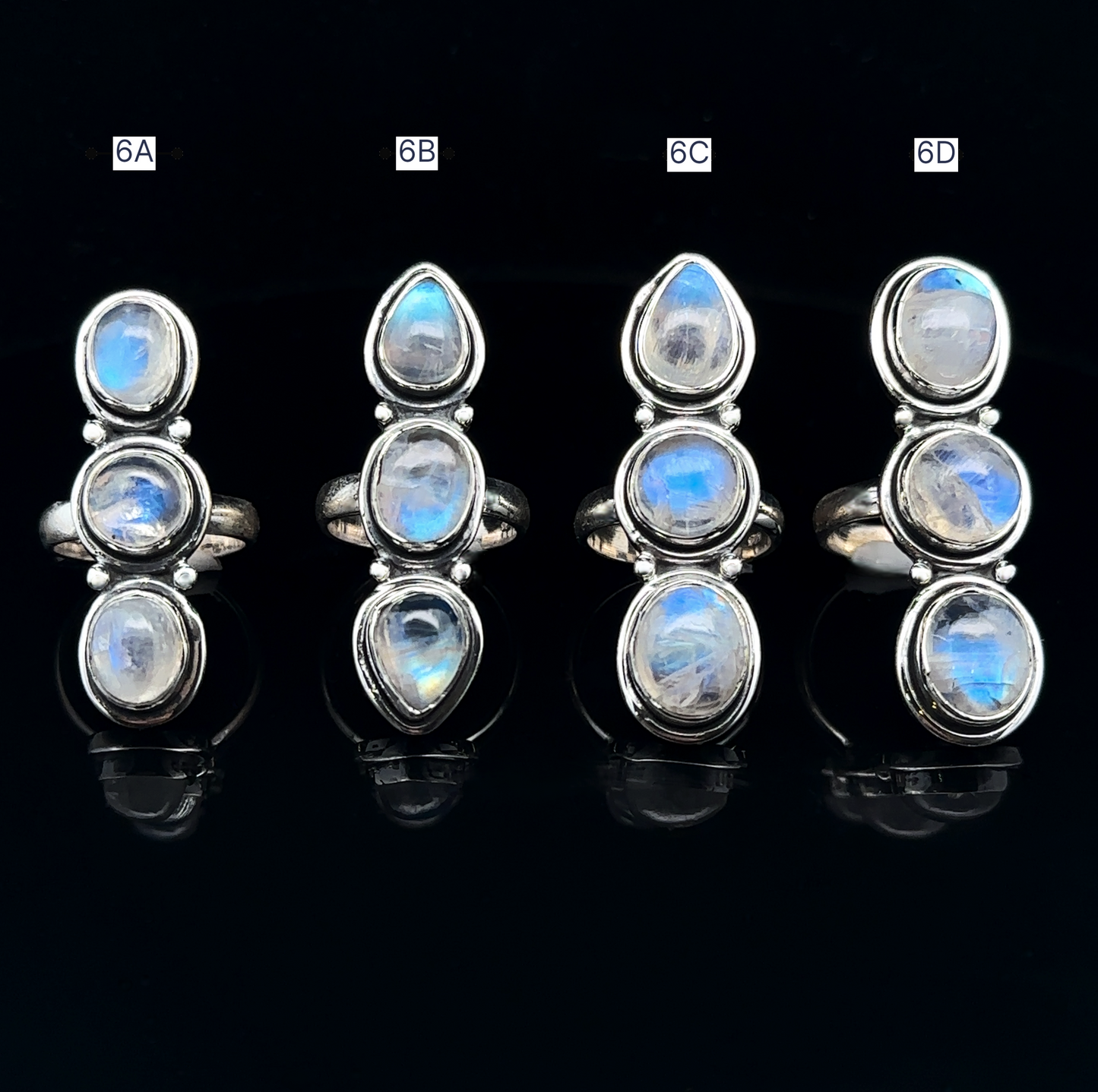 
                  
                    Four Triple Moonstone Rings crafted in sterling silver, exuding goddess energy, are labeled 6A, 6B, 6C, and 6D on a black background.
                  
                