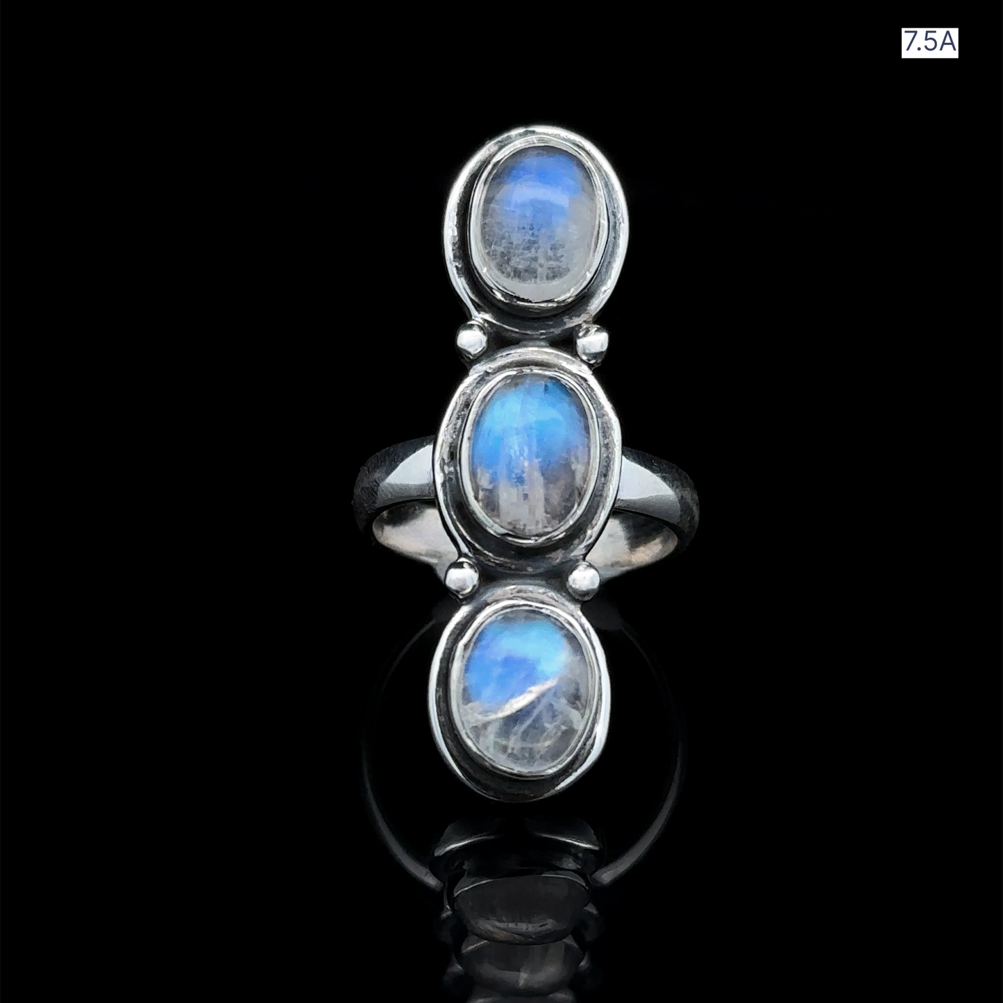 
                  
                    The Triple Moonstone Ring, crafted in sterling silver with three vertically arranged oval cabochons, radiates goddess energy against a black background.
                  
                