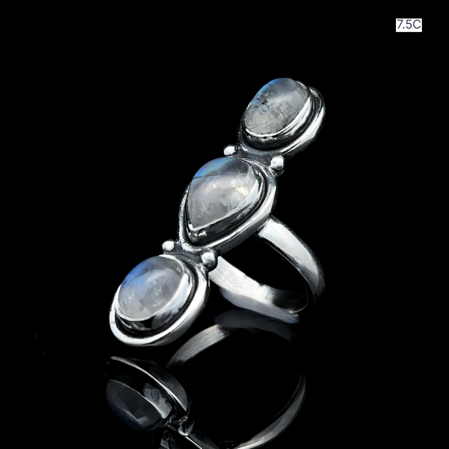 
                  
                    Emanating a goddess-like aura, the Triple Moonstone Ring showcases three oval-shaped moonstone gemstones artfully arranged on a sleek black reflective surface.
                  
                