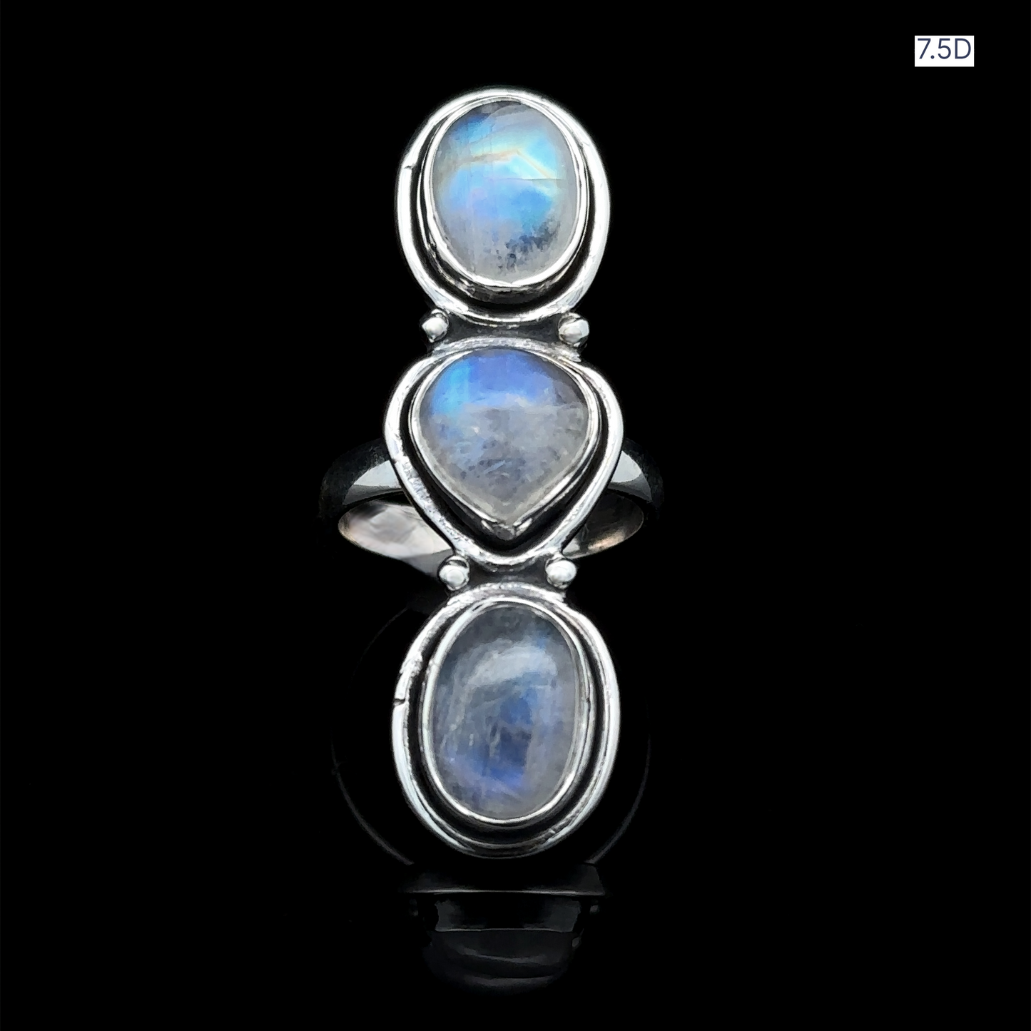 
                  
                    The Triple Moonstone Ring, crafted from sterling silver and showcasing three oval moonstones aligned on a black backdrop, emanates goddess energy. The label "7.5D" is positioned in the top right corner.
                  
                