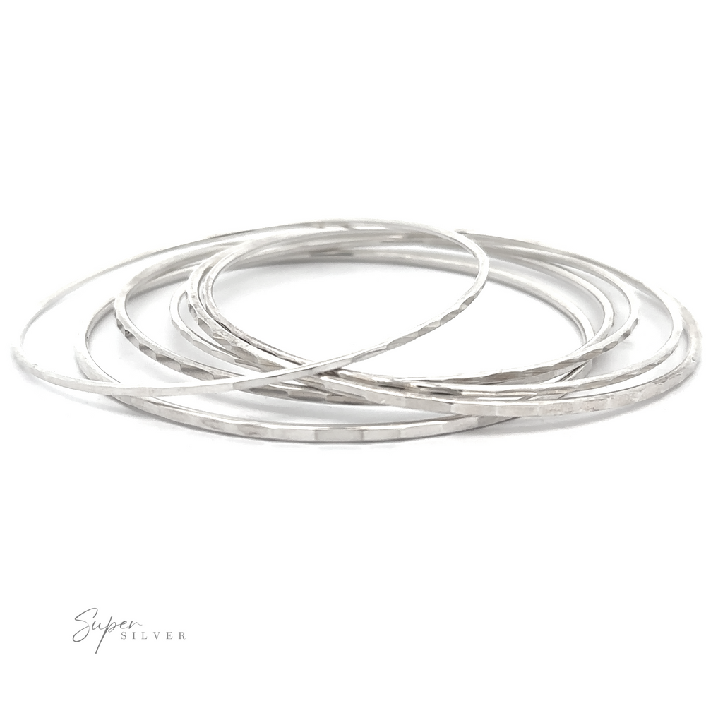 An elegant stack of Faceted Silver Bangle Bracelets, exuding a minimal vibe, set on a pristine white background.