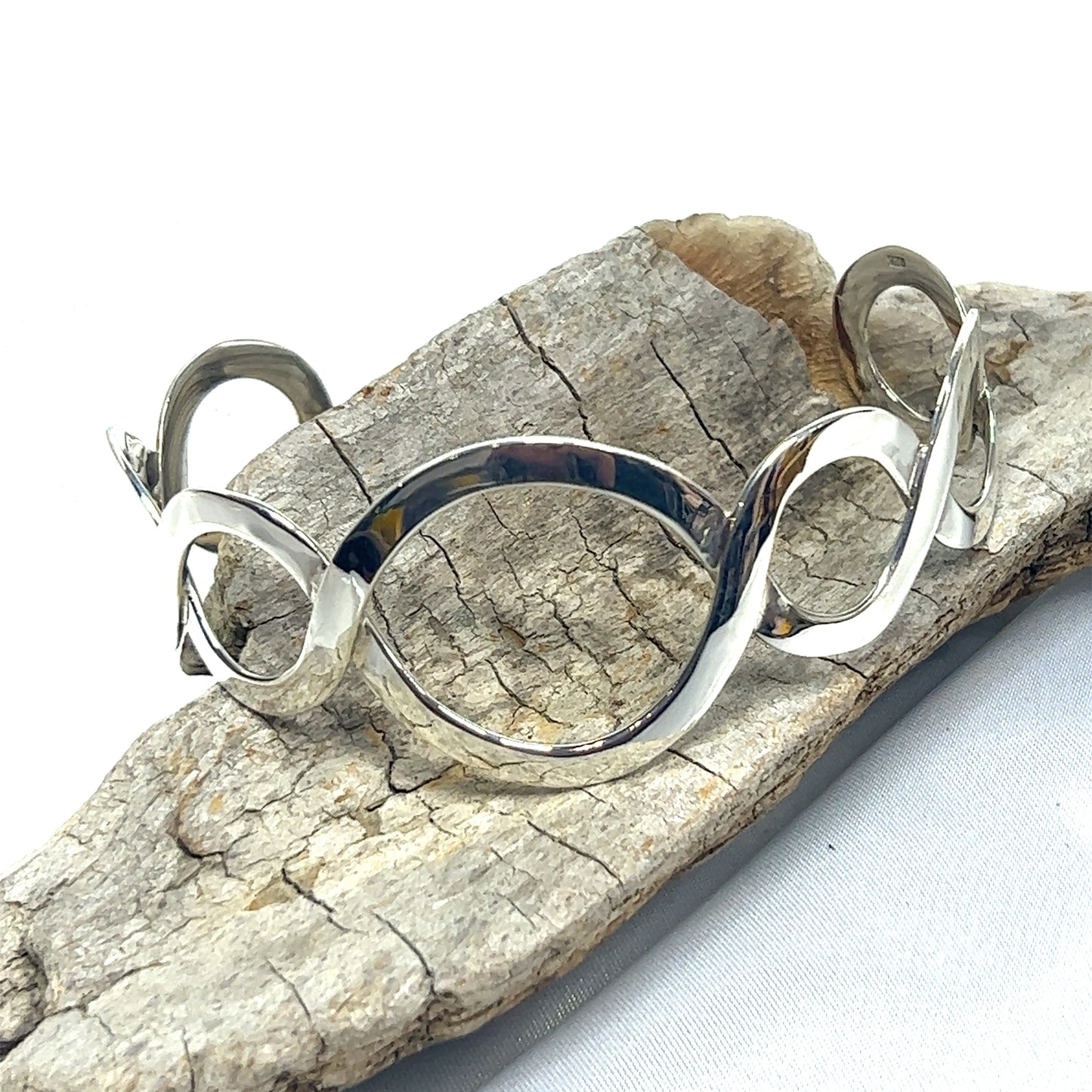 
                  
                    A Super Silver Twisted Graduated Circle Cuff bracelet, made of .925 sterling silver, sitting on a piece of rock.
                  
                