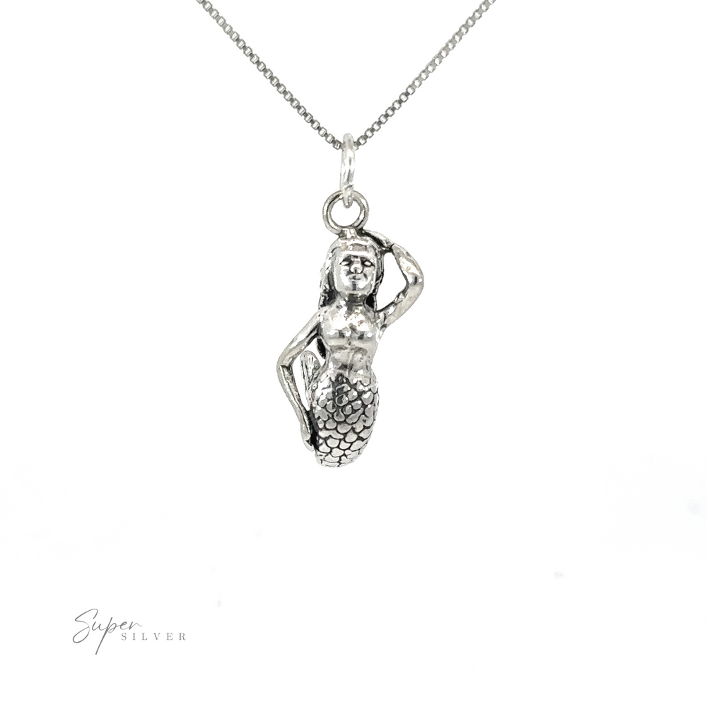 A silver Small Mermaid Charm, dripping with the enchantment of the ocean's depths, gracefully hangs from a delicate chain.