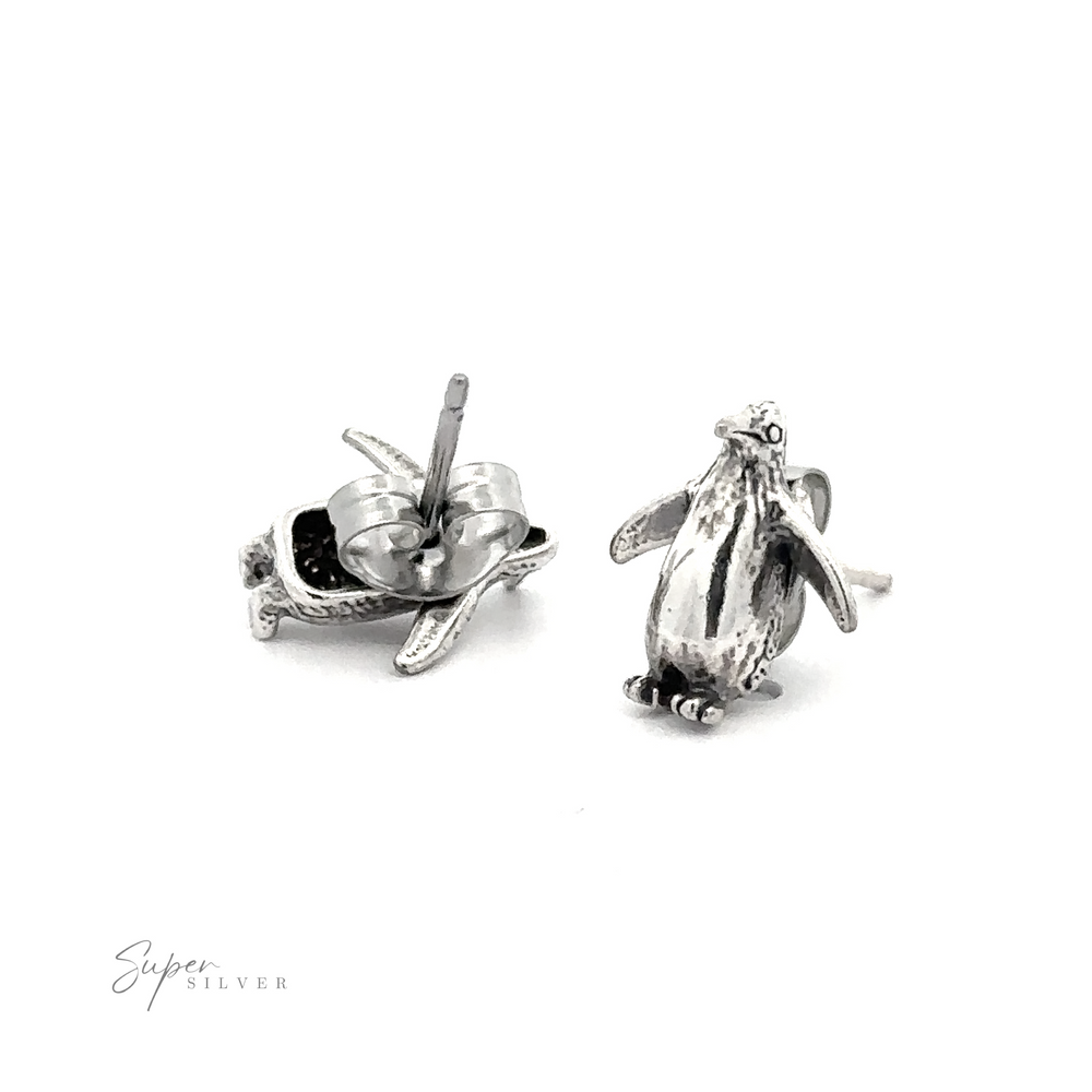 A pair of Penguin Studs made of sterling silver sitting on a white surface, perfect for bird lovers.