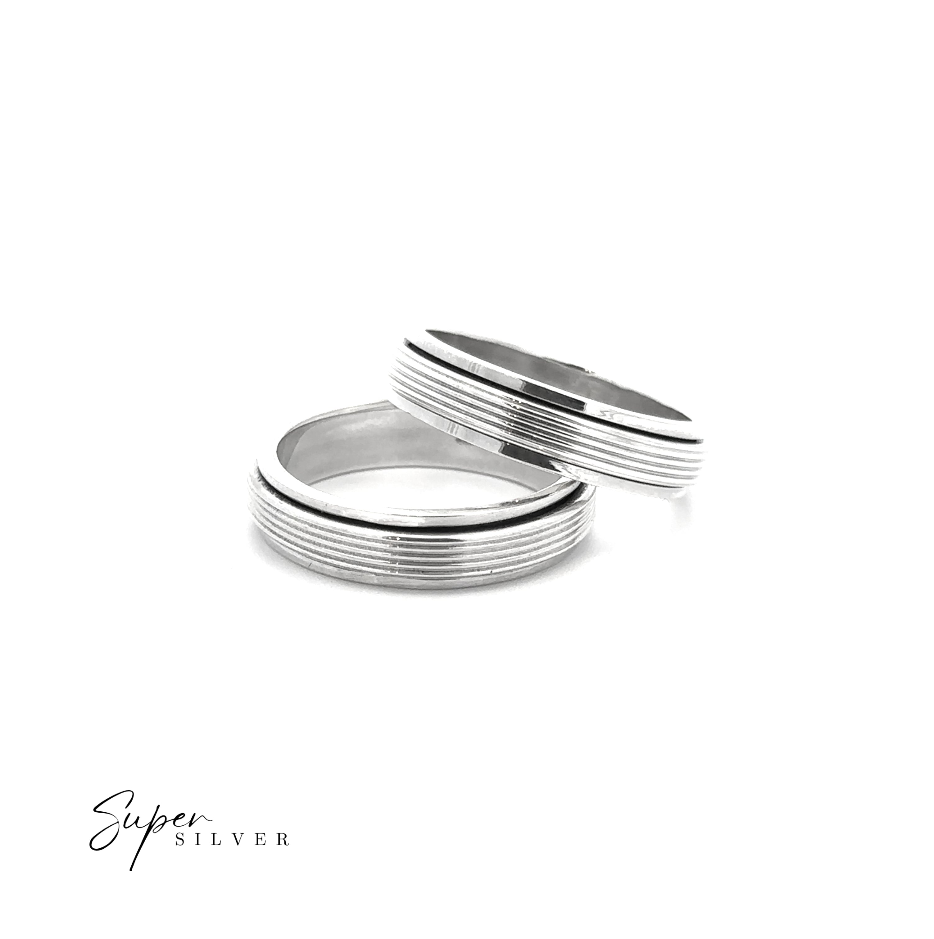 Two Striped Spinner Bands are stacked on a white background, showcasing stylish horizontal groove patterns. These sterling silver rings from "Super Silver" offer relaxation and style. The "Super Silver" logo appears in the bottom left corner.
