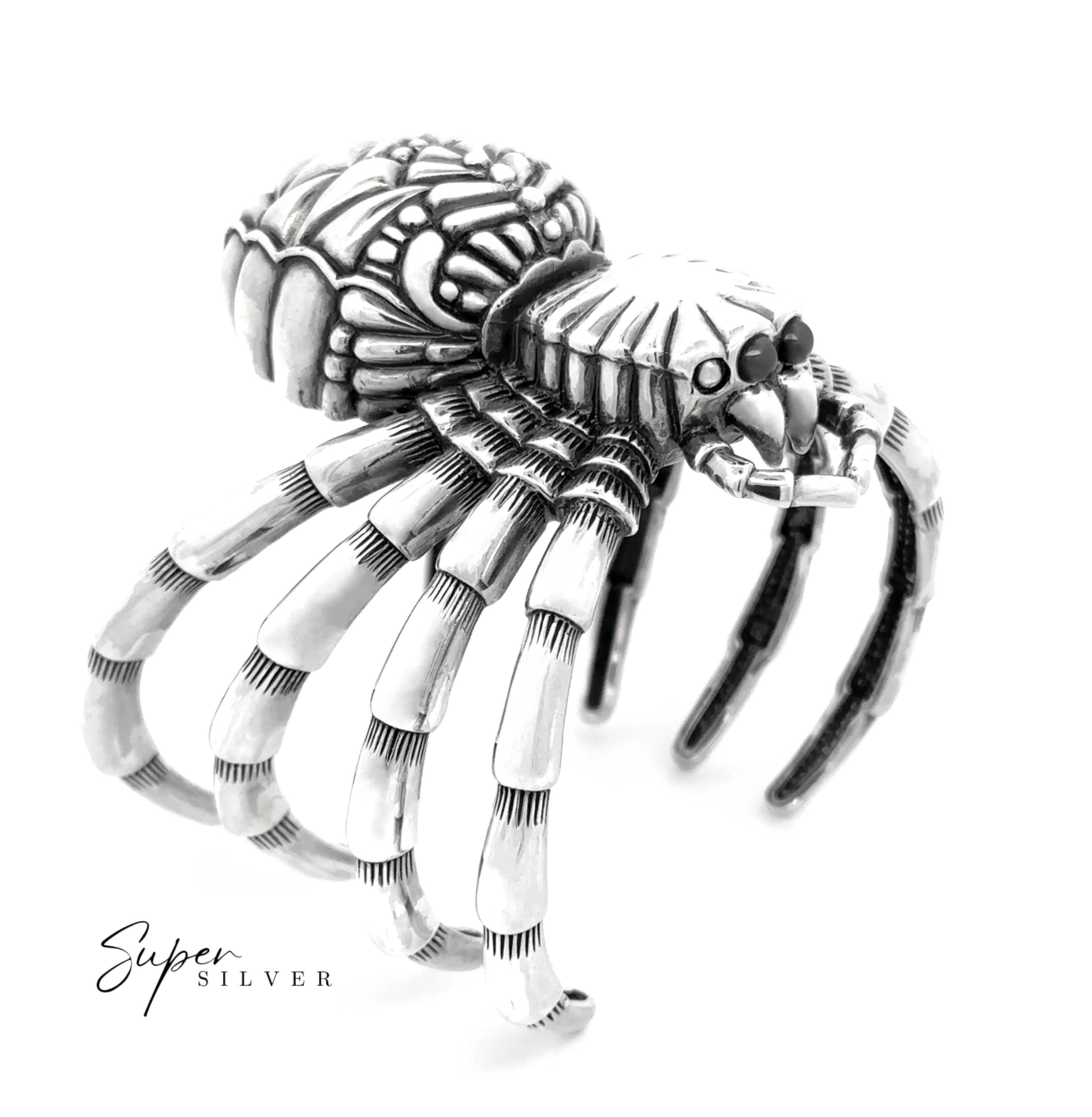 The Witch Weaver Spider Cuff, a silver bracelet with segmented legs and body, is showcased against a white background as a bold statement piece. "Super Silver" appears in the bottom left corner.