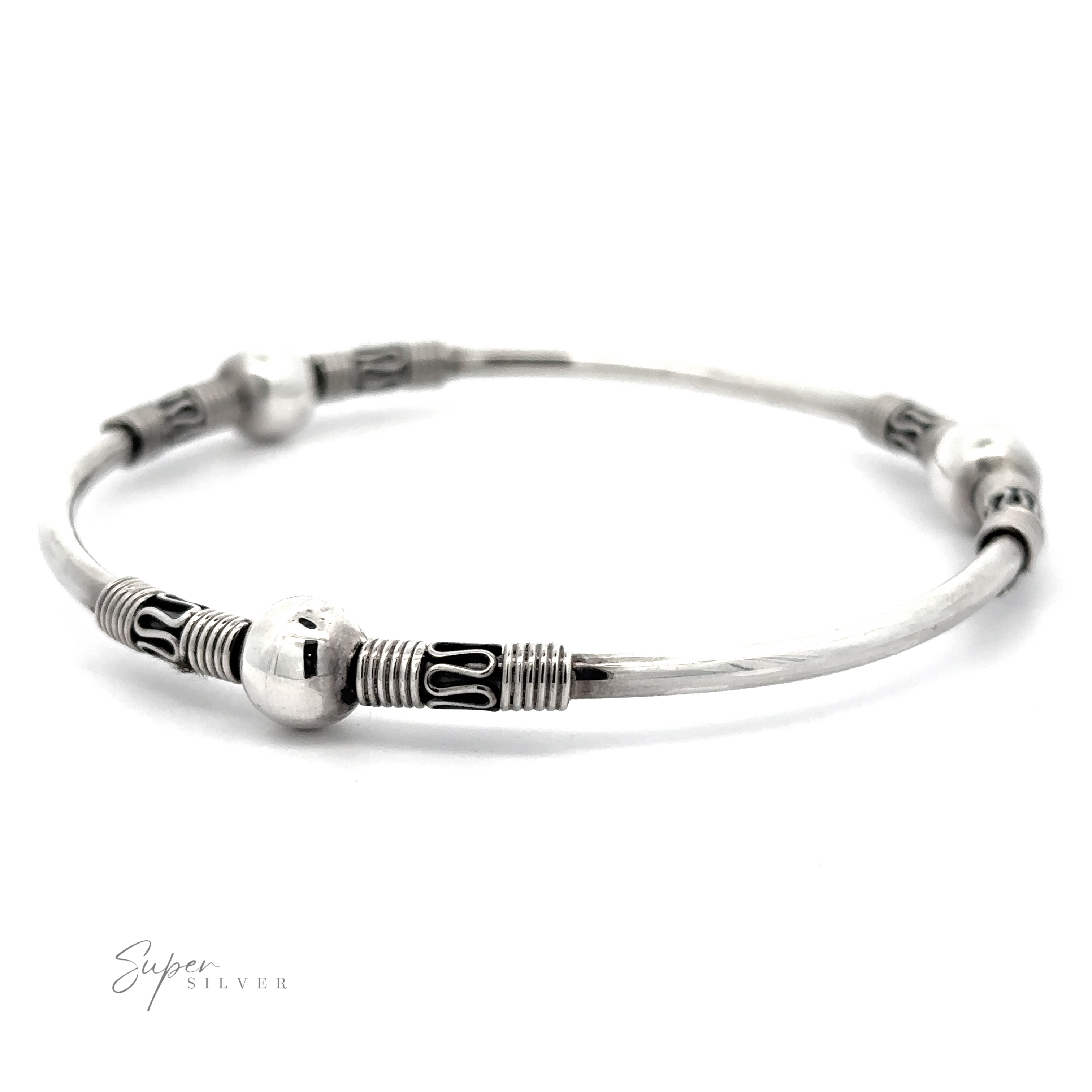 This Silver Bali Style Bangle Bracelet features decorative spherical beads and intricate etched designs, reminiscent of a Balinese style bangle.