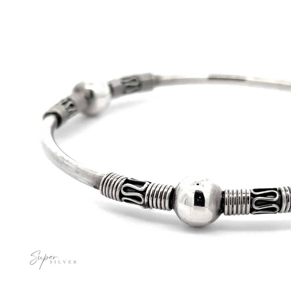 Close-up of a Silver Bali Style Bangle Bracelet with intricate designs and rounded beads. The bracelet features textured and polished elements, creating a sophisticated and elegant appearance with a subtle boho vibe.