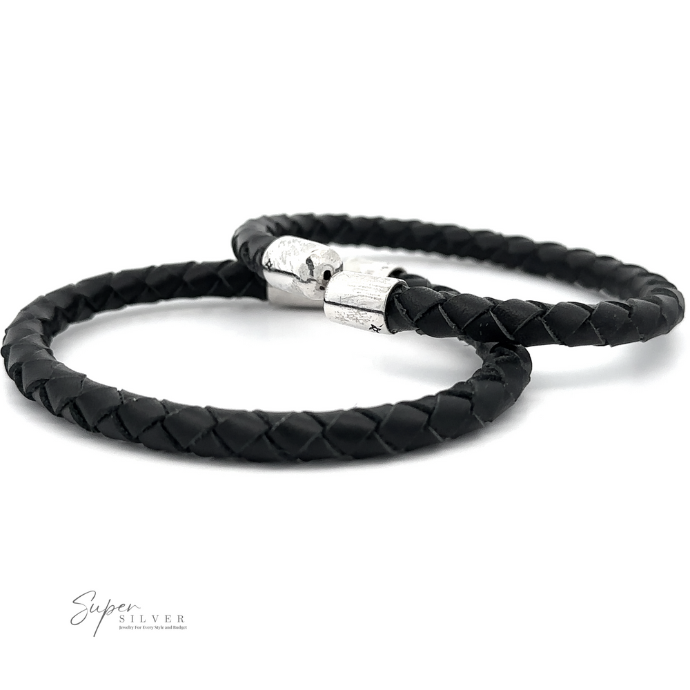 Two black Braided Leather Bracelets with sterling silver clasps are displayed. The bracelets are positioned overlapping each other on a white background. The logo 