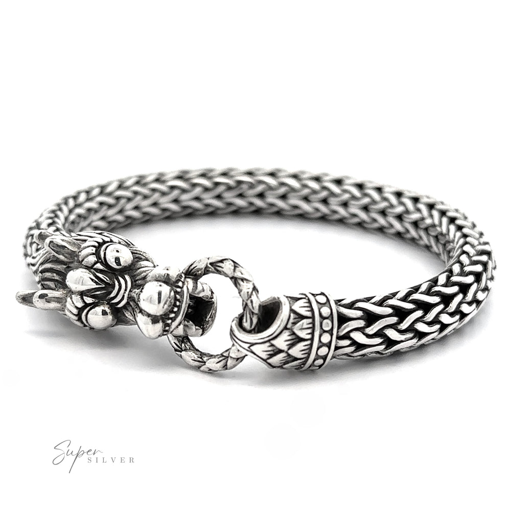 
                  
                    A Sterling Silver Braided Rope Bracelet with Dragon Head featuring a detailed clasp holding a ring, crafted from thick braided rope and .925 Sterling Silver, with "Super Silver" text in the bottom left corner.
                  
                