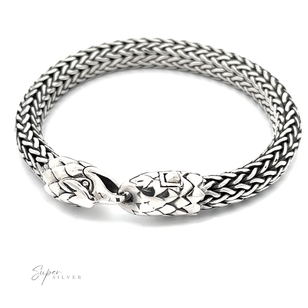 A bold bracelet crafted from .925 Sterling Silver, this piece features a woven design with two intricately designed eagle heads facing each other at the clasp.