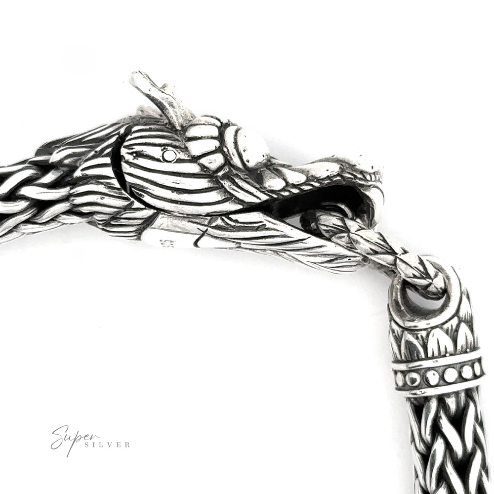 
                  
                    A detailed close-up of a Sterling Silver Braided Rope Bracelet with Dragon Head. The dragon's mouth is open, holding a ring attached to another part of the heavy-duty bracelet.
                  
                