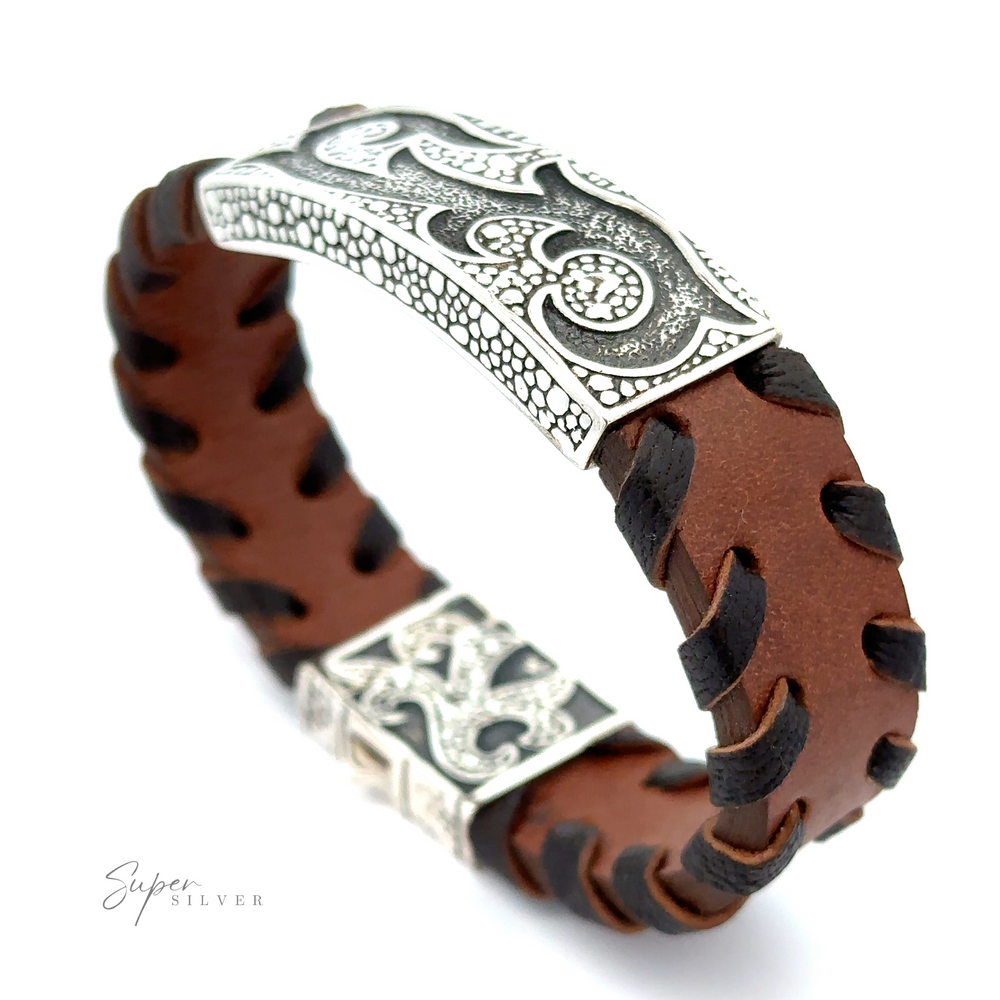 A Tribal Leather Bracelet featuring black woven detailing and a sterling silver ornamental clasp with intricate designs.