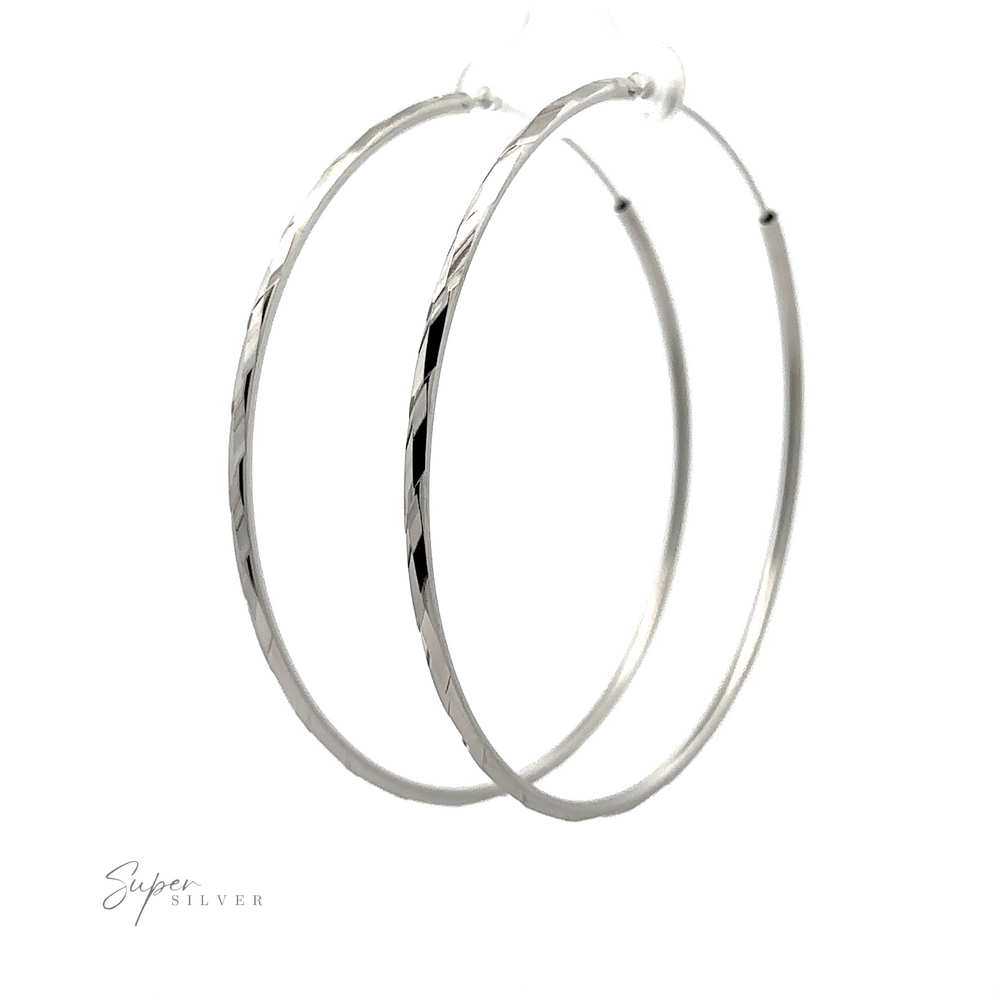 
                  
                    A pair of Brilliant 60mm Rhodium Finish Faceted Hoops displayed against a white background, with a signature "super silver" at the bottom left.
                  
                