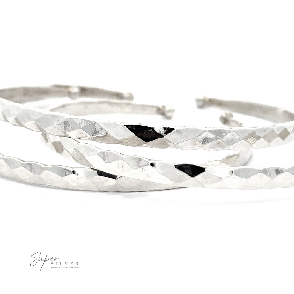 A close-up photo of two Stackable Hammered Cuffs, exuding a timeless look, placed parallel to each other on a white background. The brand 