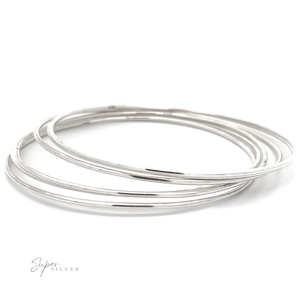 A set of three thin, smooth Plain Bangles with a polished finish, displayed overlapping each other on a white background. The minimalist charm of these Plain Bangles is undeniable. The lower left part of the image features the text "Super Silver.