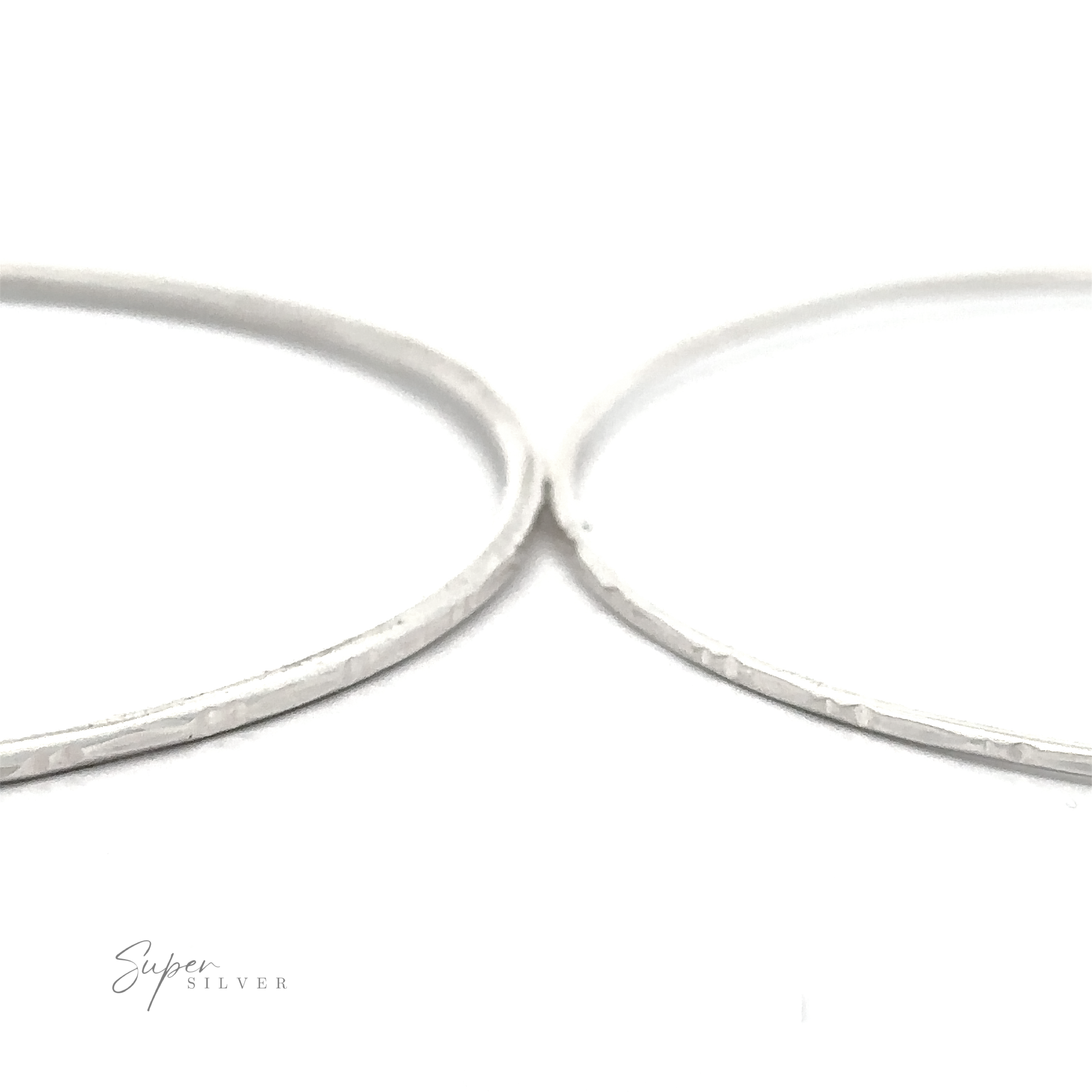 Close-up of two thin, Sparkling Faceted Bangle Bracelets with a textured surface. The background is white, and the text "Super Silver" appears in the lower left corner.