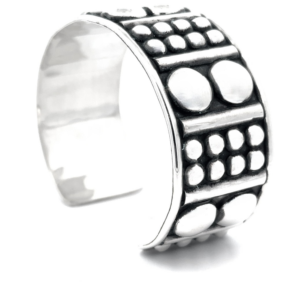 
                  
                    Sterling silver cuff with a wide band featuring an edgy design of raised circles and dots, known as the Bold Ball Patterned Cuff.
                  
                