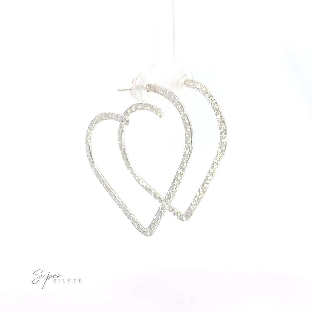 Two silver Textured Heart Hoop Earrings hanging on a white background.