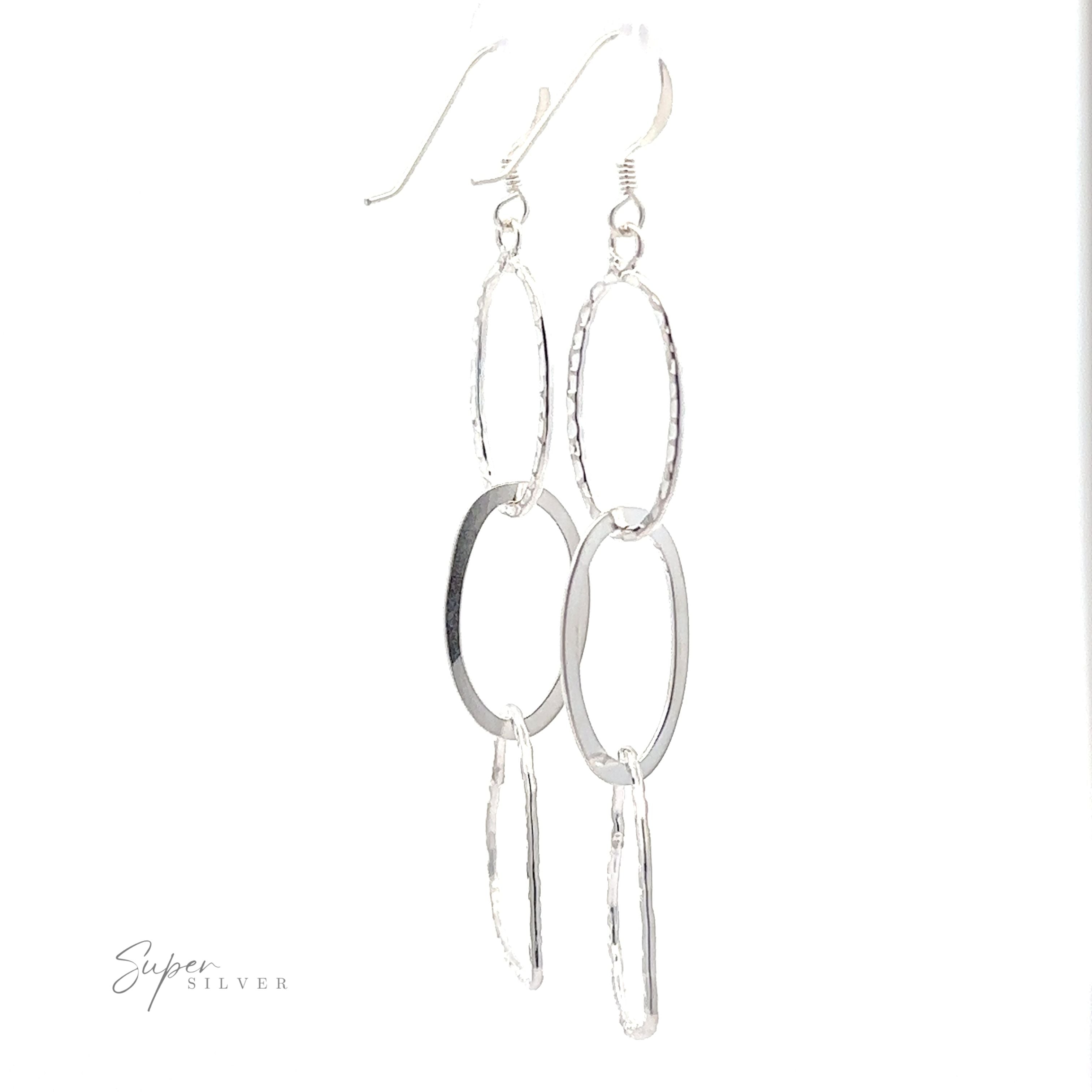 Hammered Three Tiered Heart Dangle Earrings on a white background.