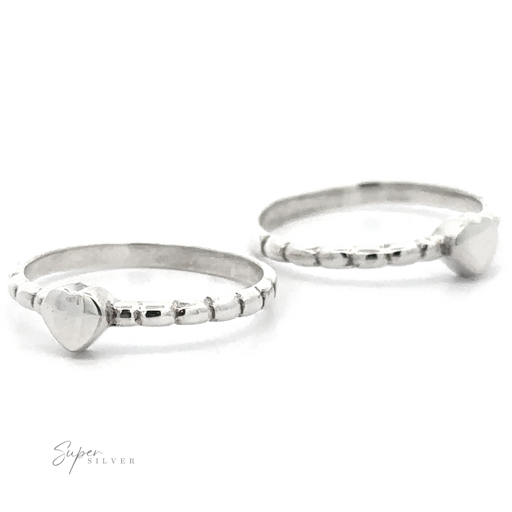 Two Petite Patterned Heart Band rings, displayed against a white background with focus on the foreground ring.