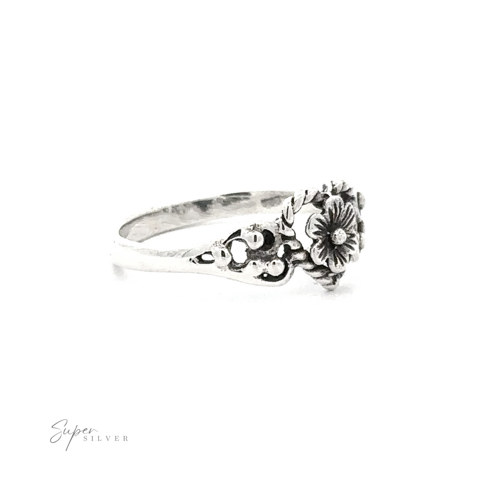 
                  
                    Twisted Heart Outline Ring with Floral Detailing featuring detailed blooms and leaves, with a signature in the bottom right corner on a white background.
                  
                