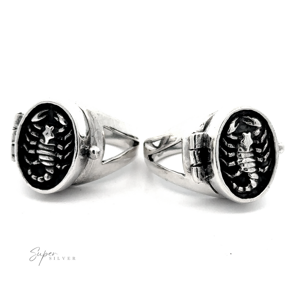 Scorpion Poison Ring: A pair of .925 Sterling Silver rings with an engraved design in the shape of fish bones on black ovals, displayed against a white background. The engraving includes a small star above the fish bones, reminiscent of Scorpio zodiac symbolism.