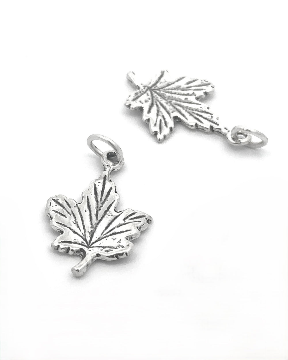 Add a touch of autumn style to any accessory with two Tiny Maple Leaf Charms, crafted in sterling silver and featuring intricate vein patterns and a small loop for easy attachment.