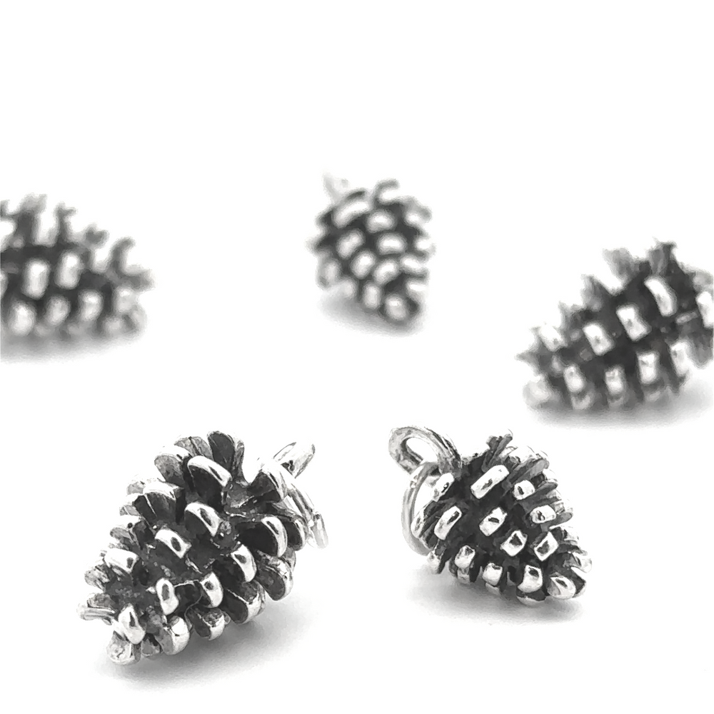 
                  
                    The Pinecone Pendant, made of sterling silver, is scattered on a white surface, making it the perfect accessory for nature lovers.
                  
                