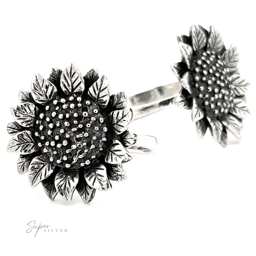 Large Sunflower Ring-shaped sterling silver ring and stud earrings with substantial setting and detailed petal and center textures, displayed on a white background with the logo 