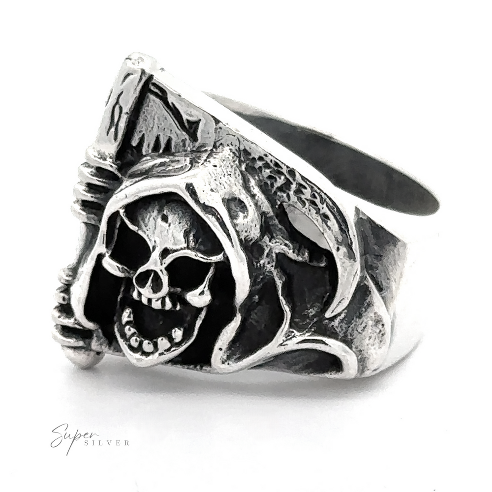 A Sterling Silver ring featuring a detailed carving of a skull wearing a hood and holding a scythe. This Grim Reaper With Scythe Ring is an intricate statement piece with noticeable engravings, and the brand name 
