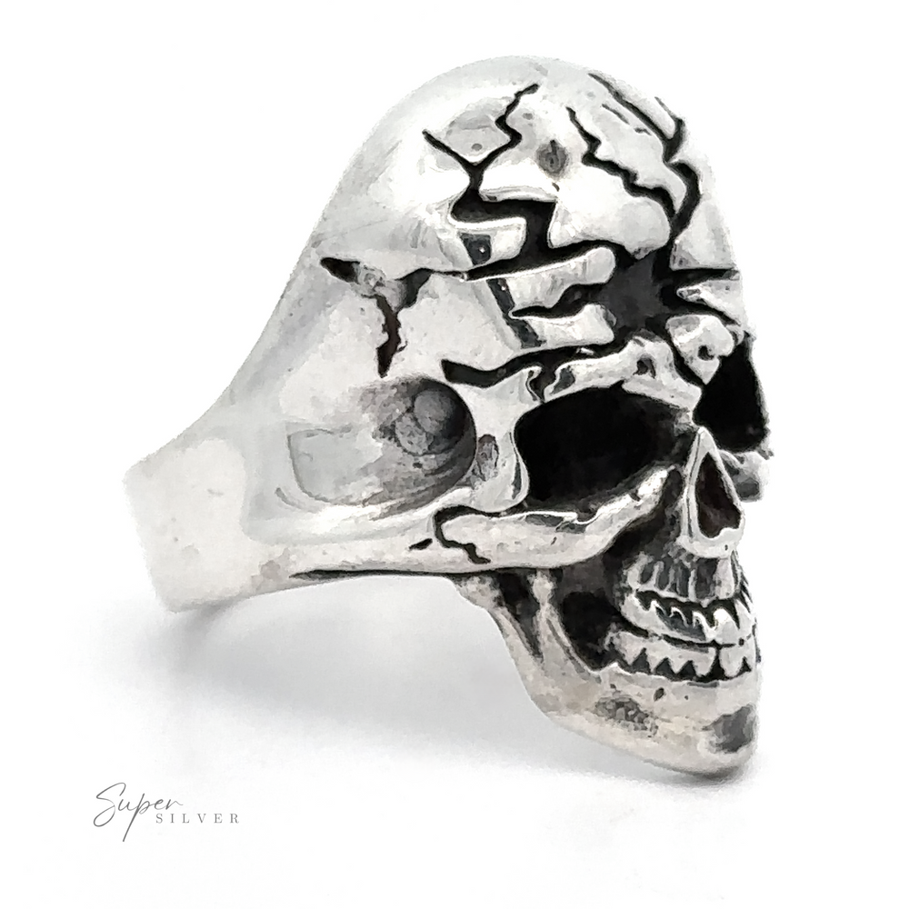 A Cracked Skull Statement Ring in silver, designed to resemble a detailed skull with cracks, showcasing rebellious elegance. The band is polished and smooth, embodying edgy sophistication.
