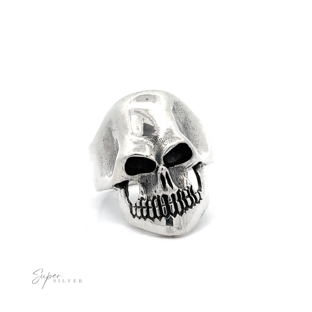 
                  
                    A silver skull-shaped ring with hollow eye sockets and detailed teeth design, exuding edgy elegance, displayed against a plain white background. The Silver Skull Statement Ring features the brand name "Super Silver" in the bottom left corner.
                  
                